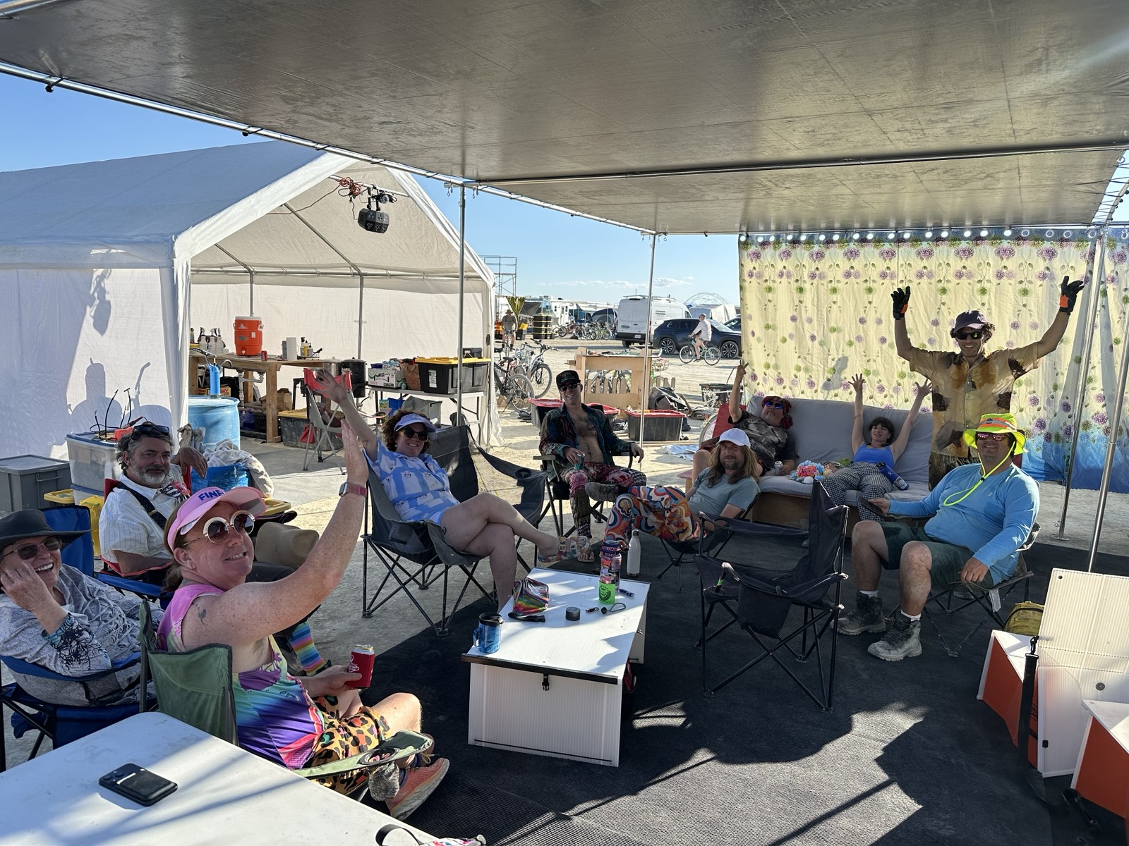 Camp life — the crew waving from under the shade structure