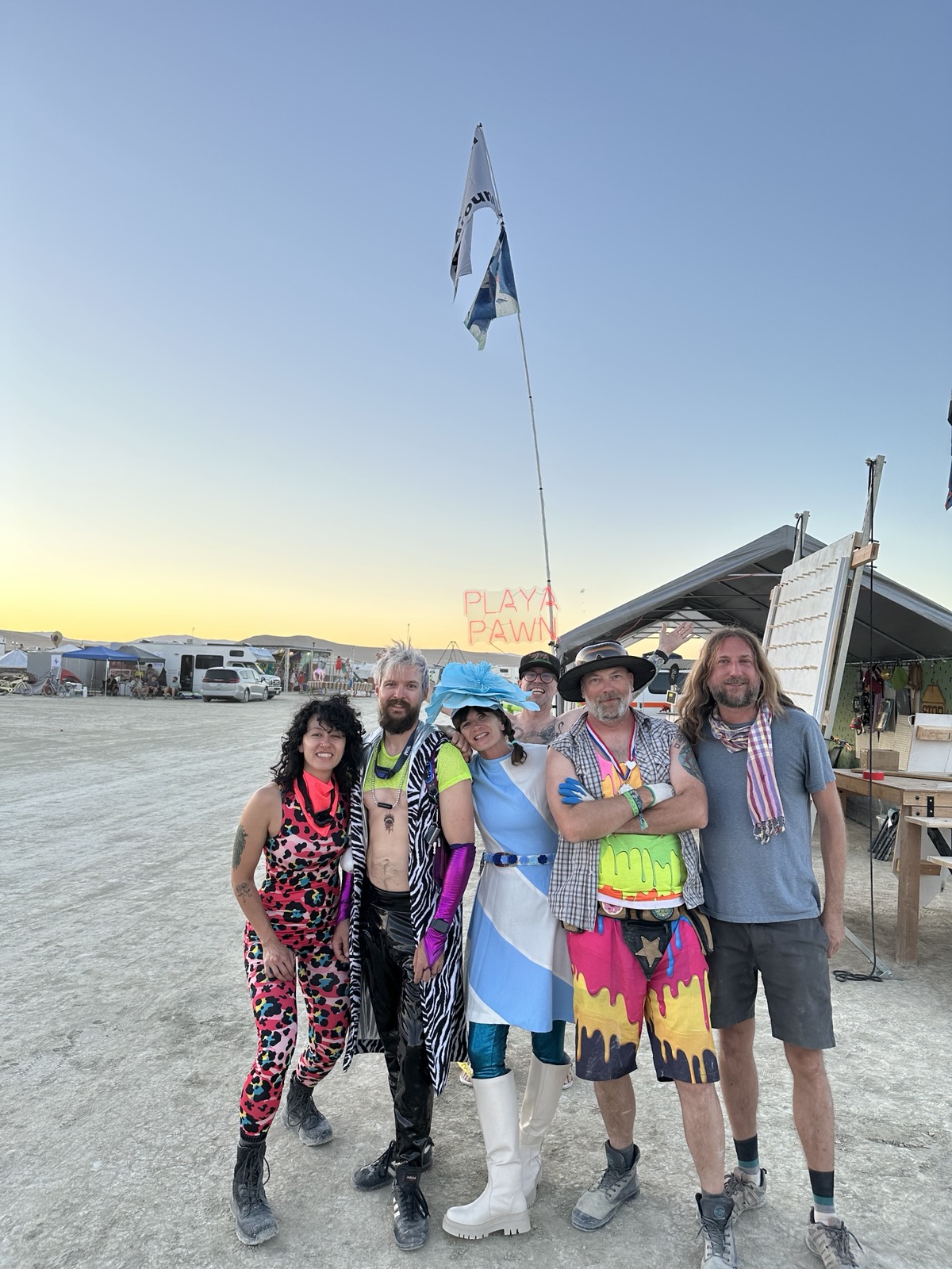 Playa Pawn crew at golden hour with the camp sign